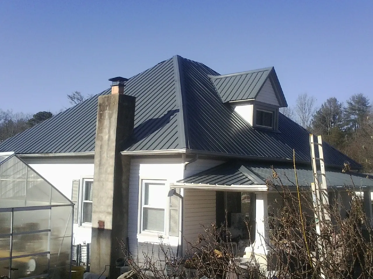 Dark blue standing seam metal roof on a white farmhouse with dormer — Slate & Tile Roof Repair by Roofing Brothers in Dundalk