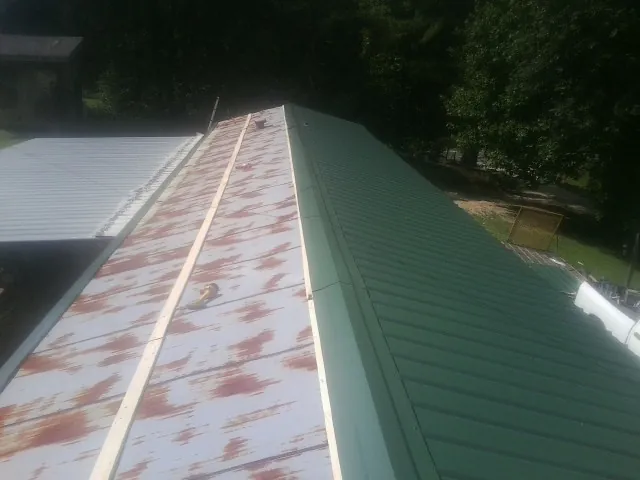 Old rusted panels beside newly installed green metal roofing — Wind Damage Roof Repair by Roofing Brothers in Dundalk