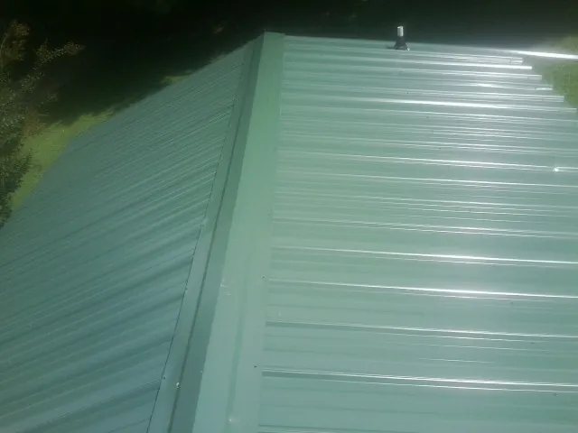 New green metal panels meeting at the ridge of a roof — Flat Roof Repair work by our crew in Dundalk
