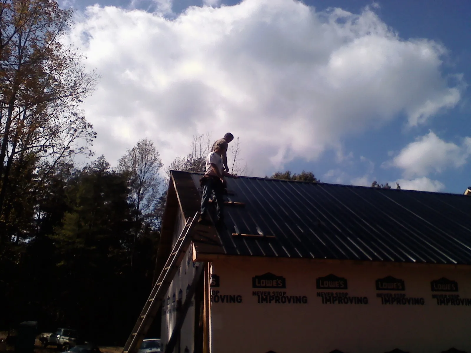 Roofer fastening dark metal panels high against a cloudy sky, from a Roof Inspection job in Dundalk
