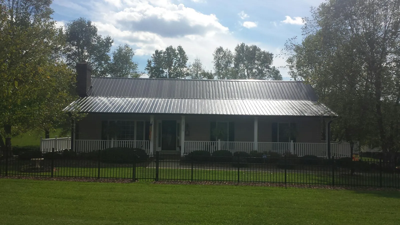 Gray metal roof on a brick ranch with a full width front porch — Gutter Guard Installation work by our crew in Dundalk