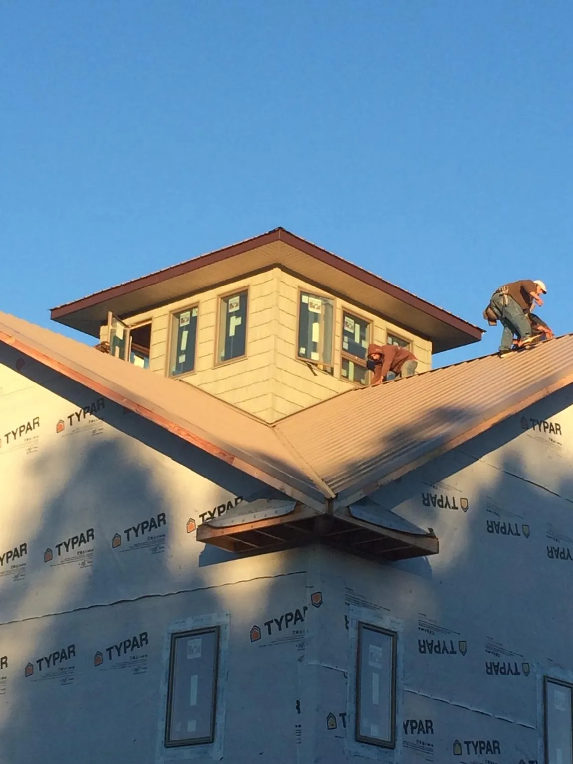 Roofers working around a rooftop cupola on a new metal roof at sunset — Roof Waterproofing in Dundalk by Roofing Brothers